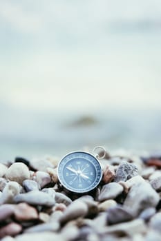 Compass on the beach, small stones, text space
