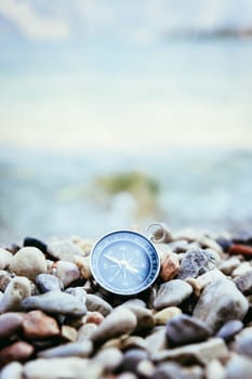 Compass on the beach, small stones, text space