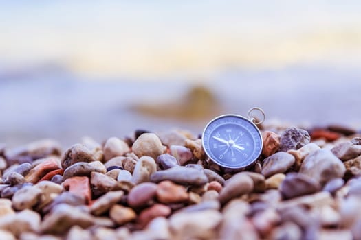 Compass on the beach, small stones, text space