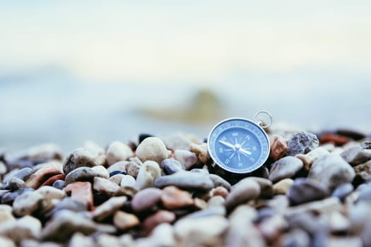 Compass on the beach, small stones, text space