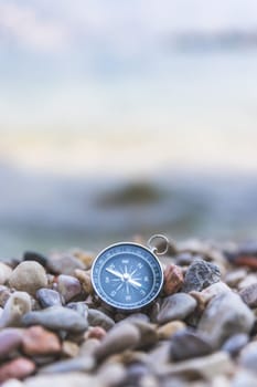 Compass on the beach, small stones, text space
