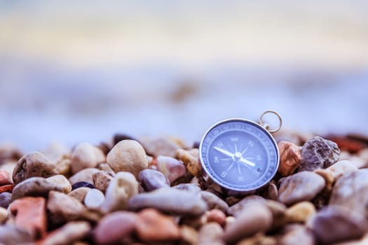Compass on the beach, small stones, text space