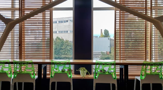 Ukraine, Kiev - September 24, 2019: Bar counter with a window. Green bar stools on a bar counter of a wooden counter near a window in a cafe