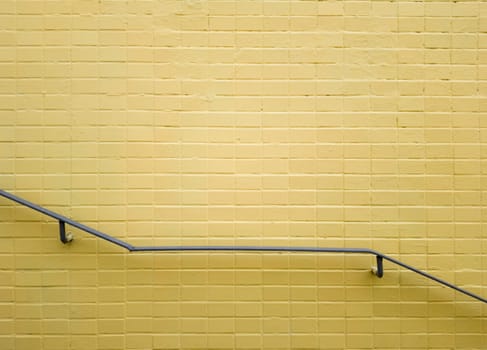 Railings of gray metal near a yellow brick wall. Yellow background, brick texture. Minimalism. Copy space.