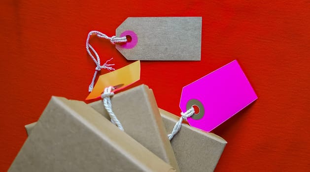Cardboard boxes with a tag. Brown packing box with blank label and copy space on red backdrop.