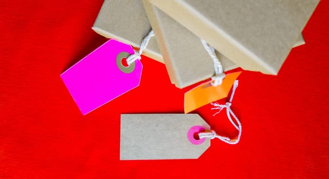 Cardboard boxes with a tag. Brown packing box with blank label and copy space on red backdrop.