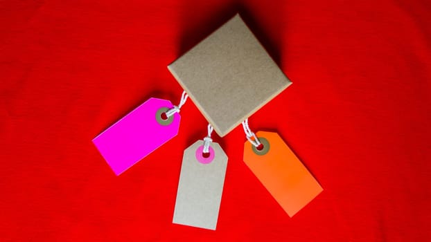 Cardboard boxes with a tag. Brown packing box with blank label and copy space on red backdrop.