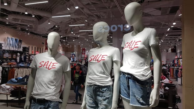 Ukraine, Kiev - September 04, 2019: Seasonal Sale, Black Friday and shopping concept. Sale signs on the stands in the store. Discount sign price on a rack in store windows. Clothes on hangers and mannequins.