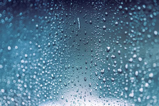 Close up of rain drops on the window in rainy night, cool lights
