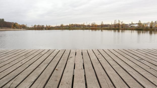 A small wooden pier on a quiet lake in the autumn foggy morning