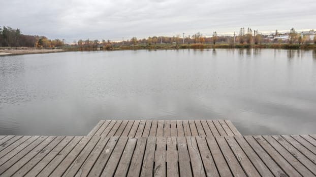 A small wooden pier on a quiet lake in the autumn foggy morning