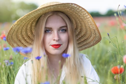 Front view portrait of smiling attractive long hair young woman posing in poppy and cornflower field. Horizontally.