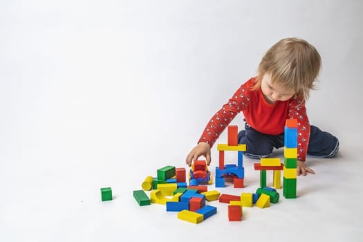 Little boy is playing with colorful wooden cubes.