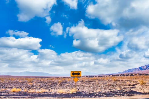 Directional sign in the desert with scenic blue sky and wide horizon. Concept for trip, freedom, holiday and transportation.