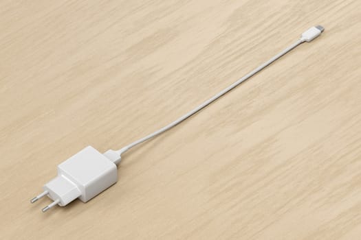 Smartphone power adapter with USB-C cable on wooden desk