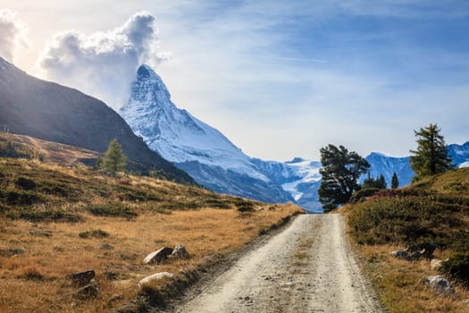A dirt road in Swiss Alps with Matterhorn in the backdrop
