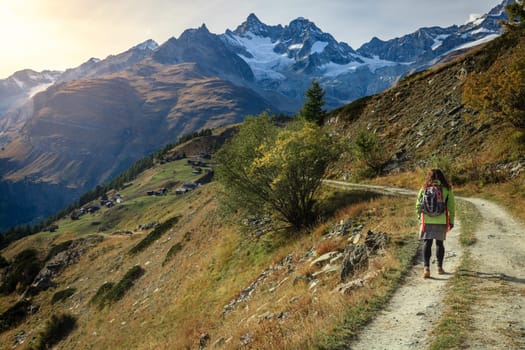 Young woman walking along a trail in the mountains near Swiss resort town of Zermatt
