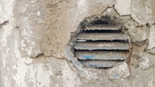 ventilation hole in concrete. Metal industrial round ventilation cover. Rusty and dirty old round ventilation frame with horizontal metal stripes