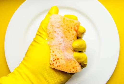Cleaning sponge on a white plate on a yellow background.