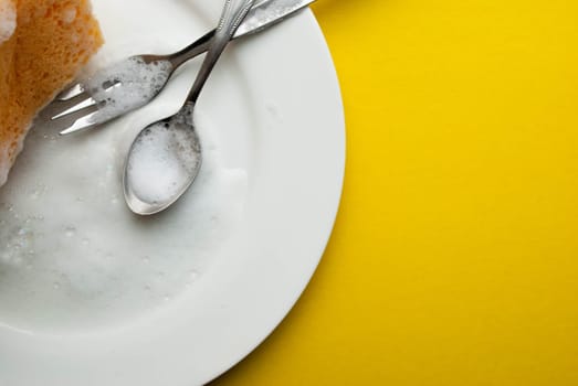 Cleaning sponge on a white plate on a yellow background.