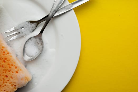 Cleaning sponge on a white plate on a yellow background.