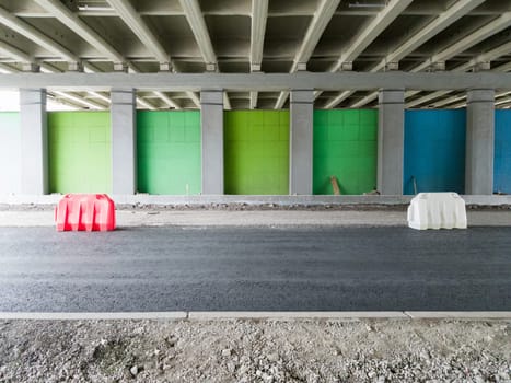 Repair of an asphalt road for cars fenced with plastic fences under the bridge. Reconstruction of the roadway in the city