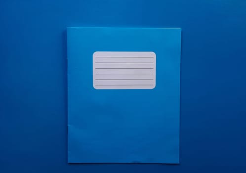 Old copybook on a blue background. School notebook, preparation for September 1 and the new school year.