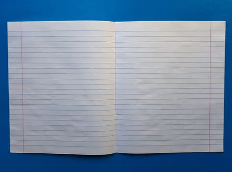 Open notebook on a white lining on a blue wooden tabletop.