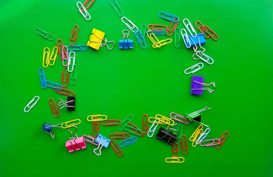 pile of paper clips isolated on green background, documents, office supplies concept, dirty office desk. Empty place for writing and text. Top view, layout. flat lay.