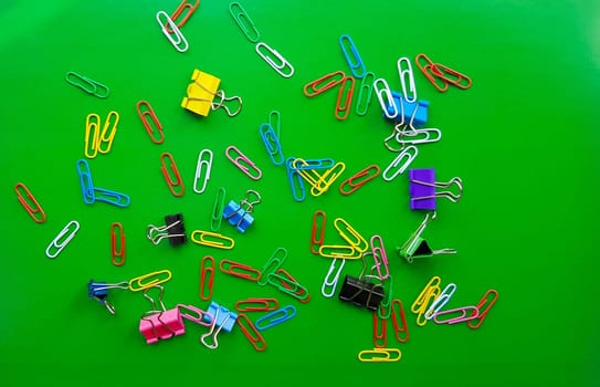 pile of paper clips isolated on green background, documents, office supplies concept, dirty office desk. Empty place for writing and text. Top view, layout. flat lay.