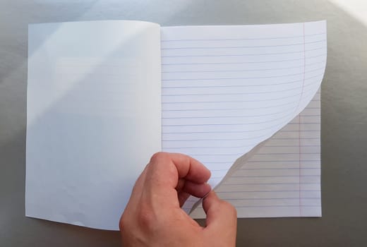 Design concept - Top view of a high quality male hand leafing through a sheet of blue striped notebook. Top view, copy space, flat lay.