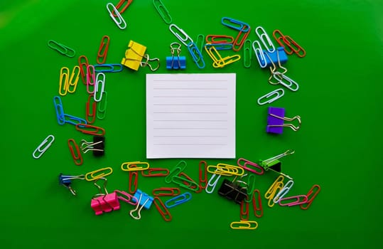 pile of paper clips isolated on green background, documents, office supplies concept, dirty office desk. Empty place for writing and text. Top view, layout. flat lay.