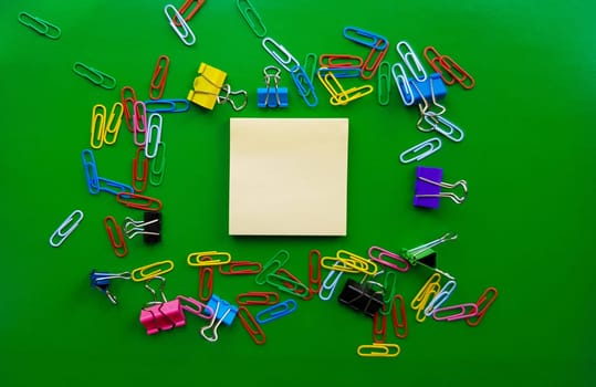 pile of paper clips isolated on green background, documents, office supplies concept, dirty office desk. Empty place for writing and text. Top view, layout. flat lay.