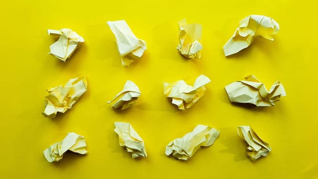 Ball crumpled paper ball isolated on a yellow background. Crumpled paper for texture. Crumpled paper after a brainstorming was thrown into the bin. A piece of yellow crumpled paper on a yellow background