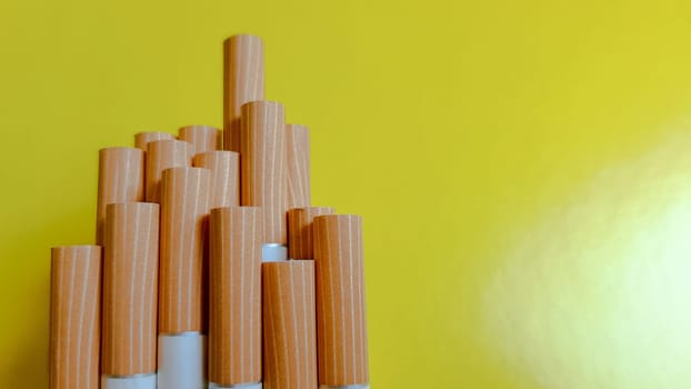 Make a cigarette. Photo of cigarette yellow filters on a yellow background. Natural light.