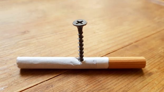 Screw and yellow background. Screw screwed into a cigarette. Anti-smoking concept.