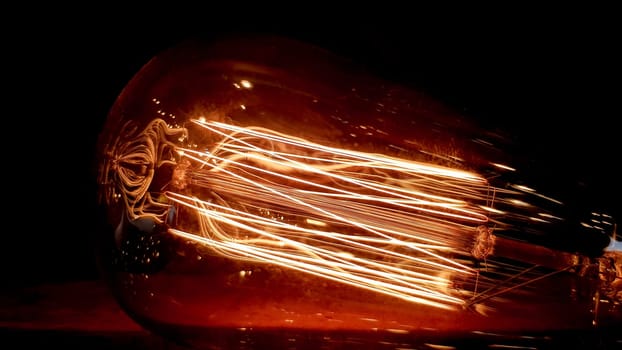 Vintage hanging edison light bulb on a dark background. Old dusty light bulbs glowing in the dark. A lamp inside a decorative glass lamp. Light begins to appear and glow in the center.
