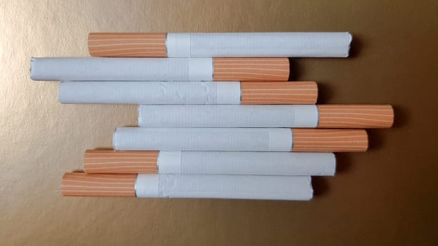Image of several commercial cigarettes. pile of cigarettes on a gold background or concept of anti-smoking campaign, tobacco.