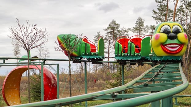 Ukraine, Kiev - October 24, 2019: roller coaster type attraction. Caterpillar-shaped roller coaster train in an amusement park. Carousels and leisure for children. Park in the fall without people.