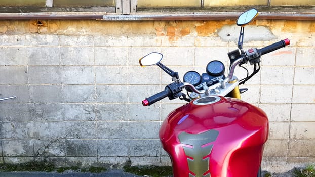 Ukraine, Kiev - September 8, 2019: Red motorcycle parked in a gray brick wall. First-person view, dashboard and steering wheel.