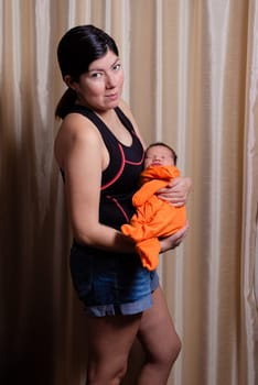 happy european young brunette mother holding her newborn baby son in her hands