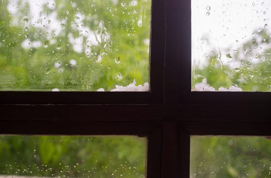Hail over wooden window frame. Selective focus over green background