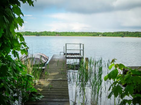 Idyllic summer shore landscape at Storkower See in Brandenburg Germany with a small jetty in the foreground and a view of the beach landscape opposite.