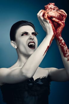 Beauty young red-haired woman brings up a human heart against grey background