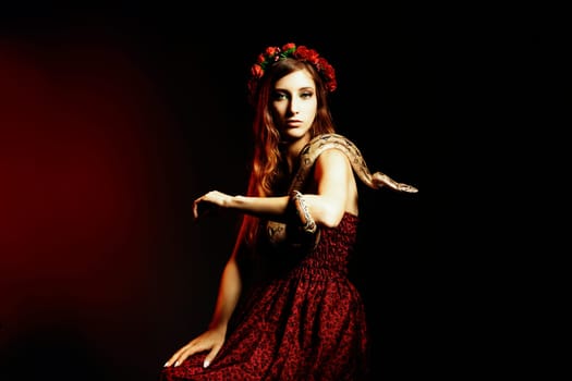 Attractive red haired woman posing with a boa constrictor