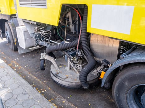 a car for cleaning roads with round brushes on a city street.