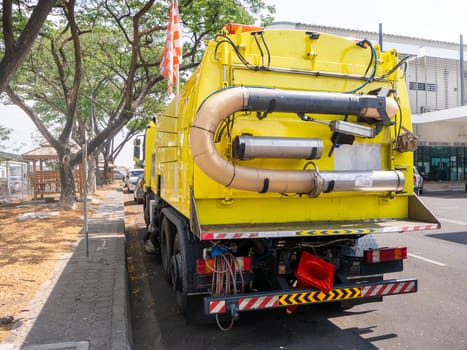 a car for cleaning roads with round brushes on a city street.
