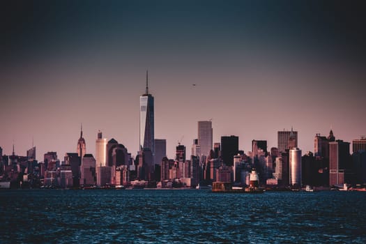 New York City Manhattan downtown skyline at dusk with skyscrapers illuminated over Hudson River panorama. Vertical composition.
