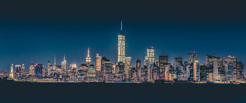 New York City Manhattan downtown skyline at dusk with skyscrapers illuminated over Hudson River panorama. Vertical composition.