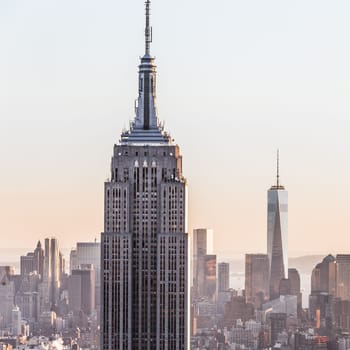 New York City. Manhattan downtown skyline with illuminated Empire State Building and skyscrapers at sunset.